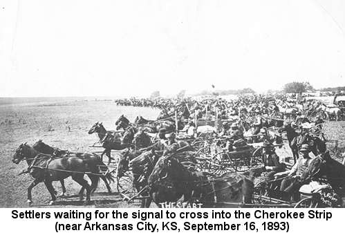 Black and white photograph of a crowd of mostly men on horseback and in wagons, waiting to the right of an invisible line; caption reads: 'Settlers waiting for the signal to cross into the Cherokee Strip (near Arkansas City, KS, September 16, 1893)'